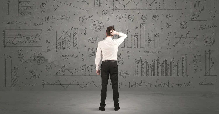 A business man is cluelessly looking at a wall full of visualized key figures