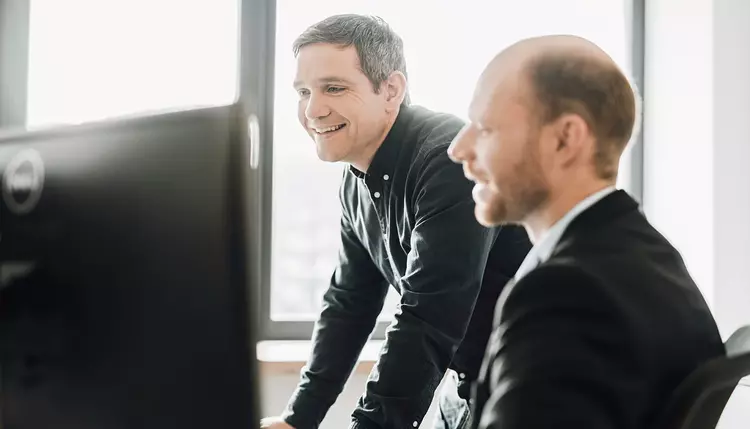 Two quality managers work on one monitor