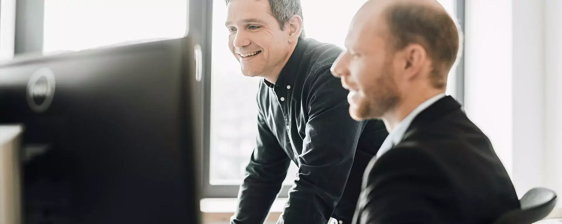 Two quality managers work on one monitor