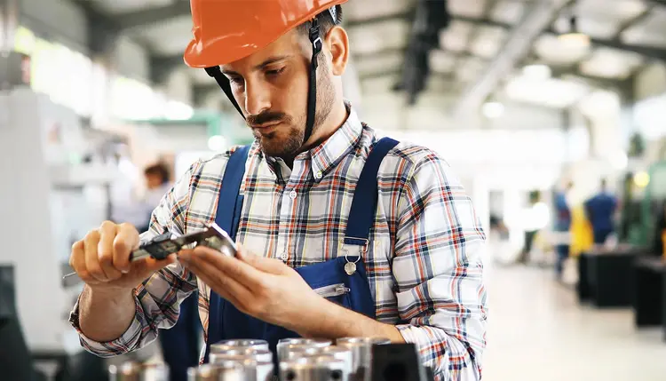 An employee checks the quality of a product with a caliper gauge