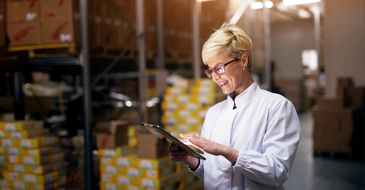 A smiling woman working on a tablet in a company